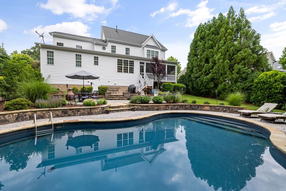 Curved pool reflecting a bright home and garden